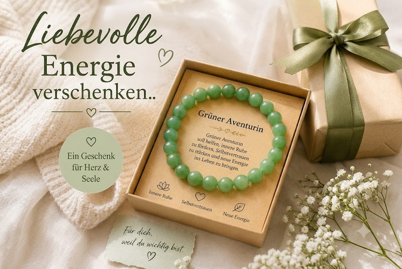 Ein elegantes Geschenkset mit einem Armband aus grünem Aventurin in einer natürlichen Kraftpapier-Geschenkbox. Umgeben von zarten weißen Blumen, einem liebevoll verpackten Geschenk mit grüner Schleife und warmem Tageslicht vermittelt das Bild Ruhe, Wertschätzung und Fürsorge. Die große Überschrift „Liebevolle Energie verschenken..“ sowie weitere deutsche Texte betonen das Armband als bedeutungsvolles Geschenk für Herz und Seele, innere Ruhe, Selbstvertrauen und neue Energie.