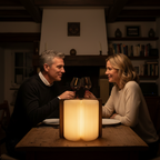 Paar genießt Wein am Esstisch mit einer LED Buchlampe aus Echtholz als romantische Tischdekoration